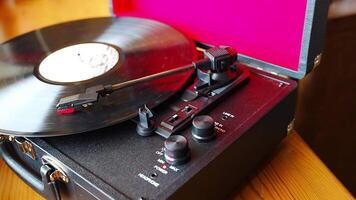 Vintage suitcase-style record player spinning vinyl record. Retro music in motion creating nostalgic atmosphere in home interior. High quality 4k footage video
