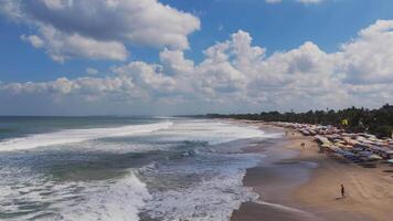 Beachfront area in Lombok with umbrellas, waves, and lush greenery video