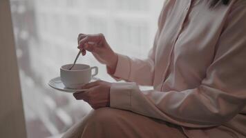 A middle-aged woman gently stirs tea in a quiet, private setting that helps induce a sense of meditative calm. video