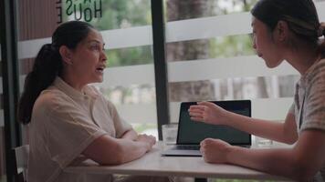 dois mulheres se empenhar dentro uma focado reunião, provável colaborando em uma projeto ou discutindo Ideias sobre uma computador portátil, criando uma sentido do profissional interação. video