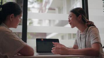 dos profesionales contratar en un colaborativo trabajo sesión, intercambiando ideas y perspectivas a un escritorio, iluminado por natural ligero mediante un ventana. video