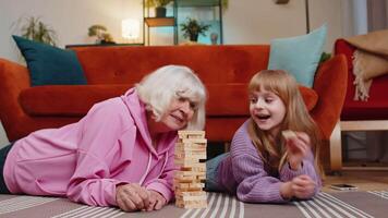 Excited little funny girl granddaughter playing building block game with smiling senior grandmother video