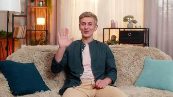Man waves hand smiles in friendly greeting hello gesture during casual talk or communication video