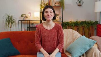 Caucasian woman smiling friendly at camera and waving hands gesturing hello hi greeting at home video