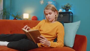 Teenager boy reading book, enthusiastically flipping pages, thoughtfully looking up, lying on sofa video