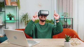 Indian man using virtual reality futuristic technology headset play simulation 3D game at home video