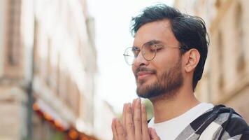 Religious Indian man praying with closed eyes to God asking for blessing while standing on street video