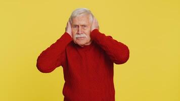 Annoyed irritated senior man covering ears gesturing no avoiding advice ignoring noise loud voices video