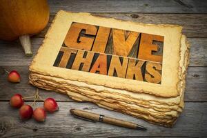 Give thanks word abstract in letterpress wood type on retro art paper with pumpkin and crab apples. Thanksgiving and fall holidays theme. photo