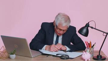 Thoughtful senior businessman making notes, writing down thoughts with pen into notepad notebook video