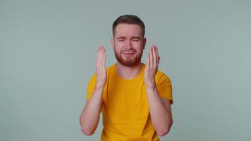 Upset disappointed man alone wipes tears and cries from despair, being sad because of unfair things video