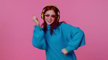 Cheerful attractive girl listening music via headphones and dancing disco fooling around having fun video