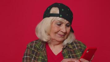 Senior woman using mobile phone typing post on web sms message browsing addiction of social networks video