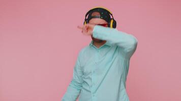 Cheerful attractive man listening music via headphones and dancing disco fooling around having fun video