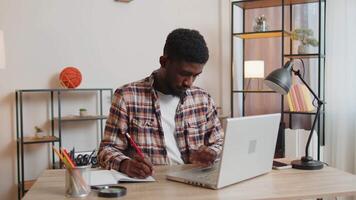 Young man guy using laptop computer sitting at table working, online shopping from home office video