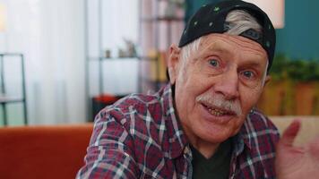 POV of senior grandfather making online call talking waving hand looking at camera at home video