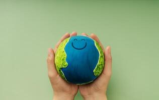 Happy Earth in hands symbolizing sustainability, global happiness, environmental care, and ecological responsibility photo