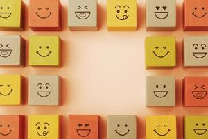 Happy Concepts. World Happiness Day, International Smiling Day. Mind and mental Health. Smiling Emoticon Face on Yellow Orange Cube. Table Top View with Copy space photo