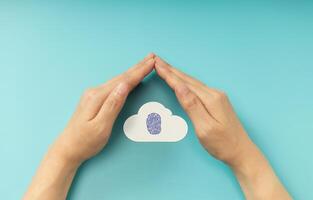 Hands shielding Fingerprint on Cloud symbol, representing Cybersecurity, data privacy, and online protection. Top View photo