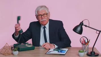 Senior businessman talking on wired vintage telephone of 80s, says hey you call me back at office video