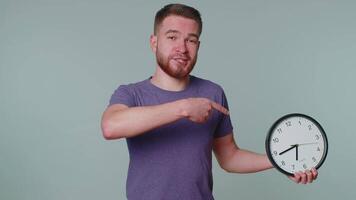 Bearded young man showing time on clock watch, ok, thumb up, approve, pointing finger at camera video