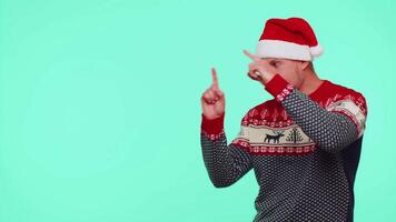 Man wears red New Year sweater deer showing thumbs up and pointing at on blank advertisement space video