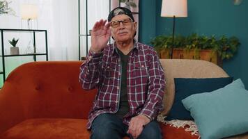 Senior grandfather smiling friendly at camera, waving hands gesturing hello, hi, greeting at home video