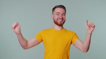 Stylish man in t-shirt shouting, raising fists in gesture I did it, celebrating success, winning video