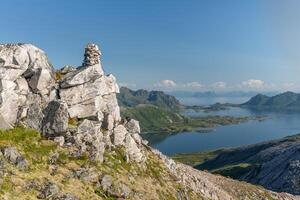 Rocky hill ridge with pyramid of stones on it and sea with islands in background, Lofoten Norway photo