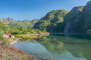 Crystal clear lake near mountains with reflections on the water with abandoned house on shore, Lofoten Norway photo