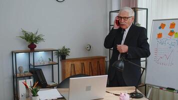 Angry senior business man making phone call at office work annoyed boss talking mobile quarrel video