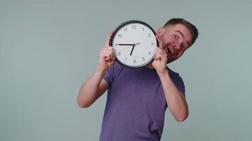 Young man holding clock watch, hiding, checking time on clock, running late to work being in delay video