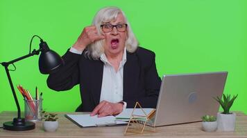 Senior office businesswoman looking at camera doing phone gesture like says hey call me back contact video