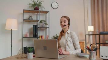 Woman with headset using laptop, talking, working customer support service operator at home office video