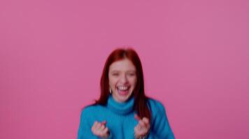 Teen girl in blue sweater shouting, raising fists in gesture I did it, celebrating success, winning video
