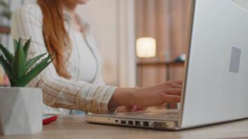 Young woman girl using laptop computer sitting at table working, typing on keyboard from home office video