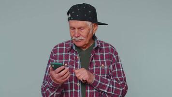 Senior man using mobile phone typing post on web sms message browsing addiction of social networks video