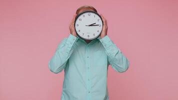 Young man holding clock watch, hiding, checking time on clock, running late to work being in delay video