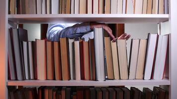 Librarian or student searching for a textbook on a white bookshelf in the library, reaching out to grab a book from the neatly organized shelves, immersed in the quest for knowledge video