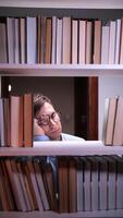 A man is sleeping on a shelf of books video