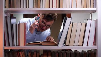 A man is reading a book while talking on a phone video