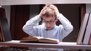 A boy with glasses is looking at a book video