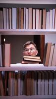 uma homem com óculos espreitar Fora a partir de atrás uma livro estante video