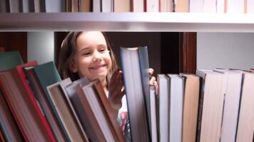 Smiling young girl searching for interesting book among many books standing on bookshelf in library, enjoying literature and reading, gaining knowledge and education video