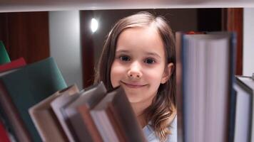 A young girl is looking at the camera while standing in front of a stack of books video