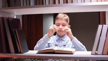 A boy in glasses is looking at a book video