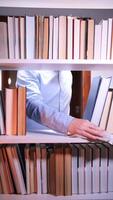 A person is reaching for a book on a shelf video