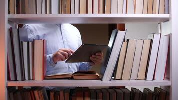 A man is using a tablet computer in front of a book shelf video