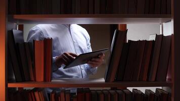 A man is using a tablet computer in a library video