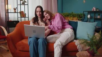 Young adult women couple looking at laptop notebook screen making online shopping purchase at home video